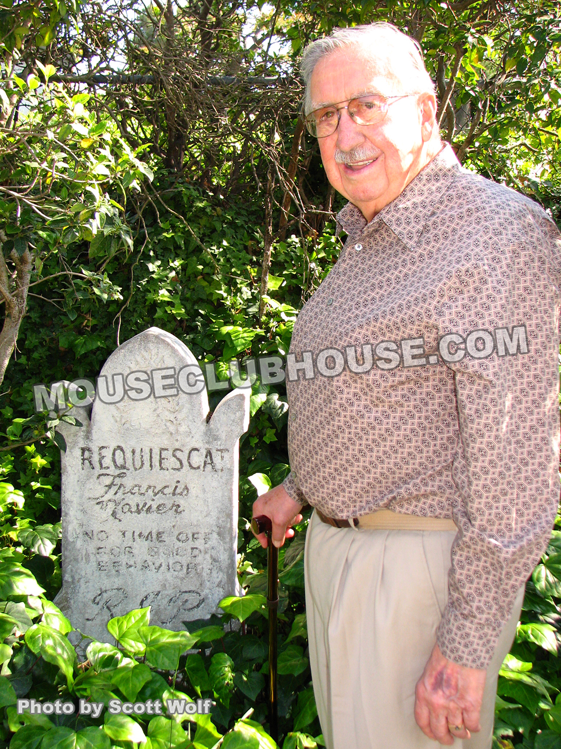 X Atencio stands by the tombstone tribute to him that used to reside outside the Haunted Mansion in Disneyland, but is now in his home backyard