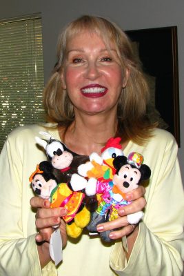 Alyja holds dolls wearing her costumes she designed for a parade. These were sold in Tokyo Disneyland. 